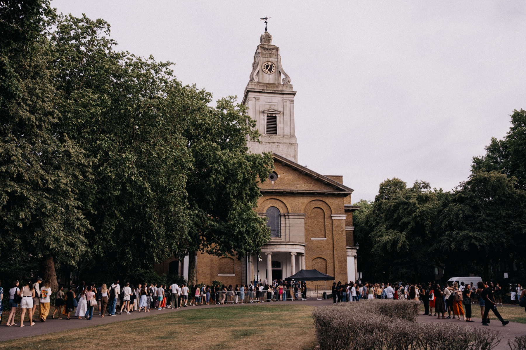 Hackney Church surrounded by trees with people gathering outside